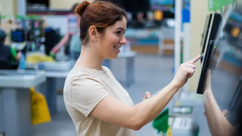 A happy customer using a self-checkout machine