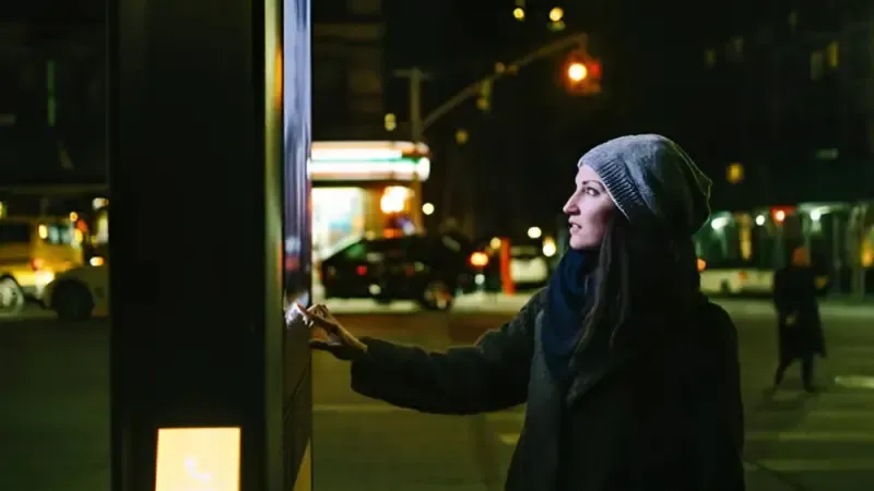 A woman using a digital kiosk placed in a park
