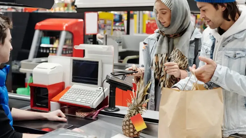 a couple paying for groceries at a traditional cash register