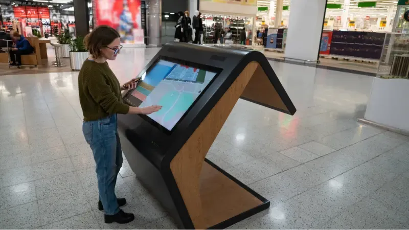 a woman using a self-service kiosk inside a building