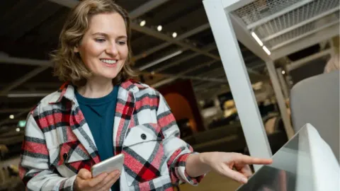 A customer happily using a self-service kiosk