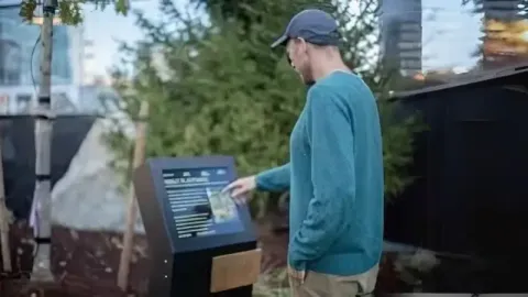 A man navigating the map of a park using a digital kiosk