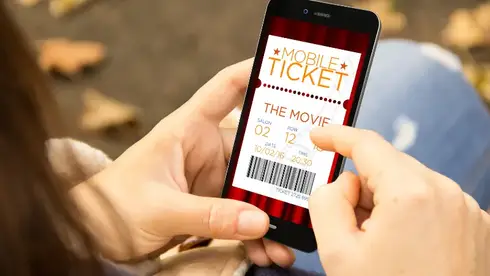 A woman reservation cinema e-ticket with a smartphone in the park