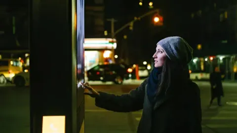 A woman using a digital kiosk placed in a park