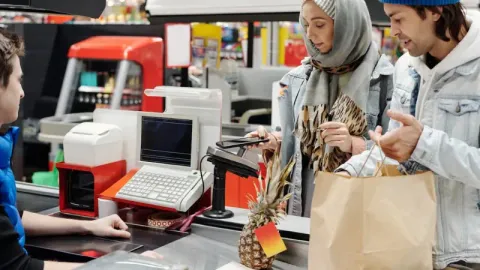 a couple paying for groceries at a traditional cash register