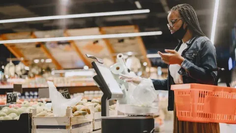 a customer interacting with a self-service kiosk at a supermarket