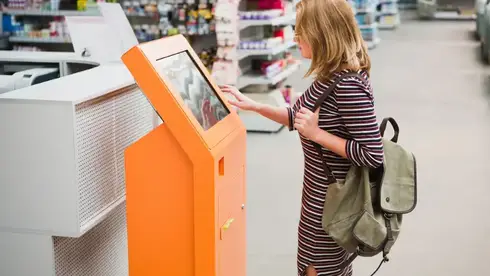 a woman using a payment kiosk at a grocery store