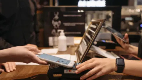 A Person Tapping the Phone on a Payment Terminal