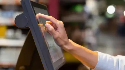 A customer using a price checking machine in a retail store