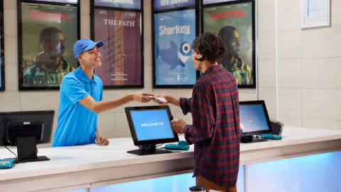 A staff member serving a customer at the ticketing kiosk