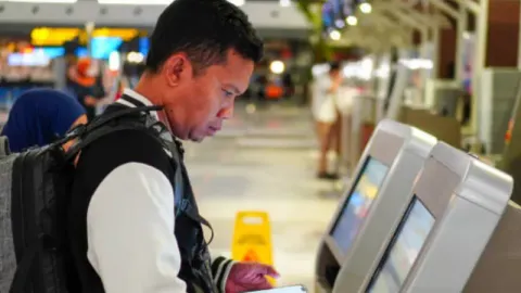 An elderly user using a self-service kiosk at the airport