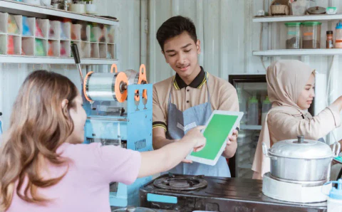 The store owner guiding the customer to pay on mobile