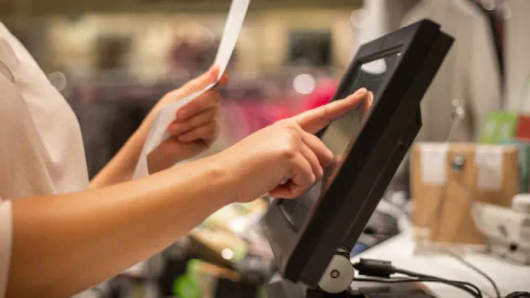 a shopkeeper putting in the item in a POS system