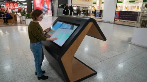 a woman using a self-service kiosk inside a building